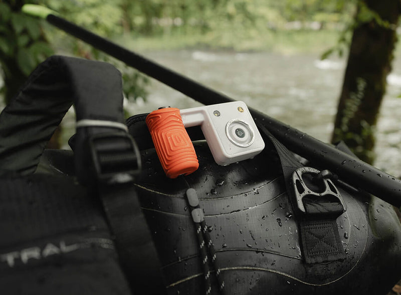 Portal AFN7 with an orange grip resting on a wet dry bag by a river