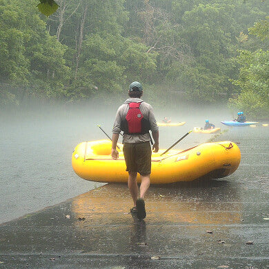 Rafter walking toward a yellow raft on a misty river