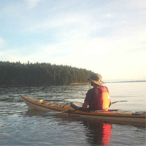 Kayaker paddling a calm bay at sunset
