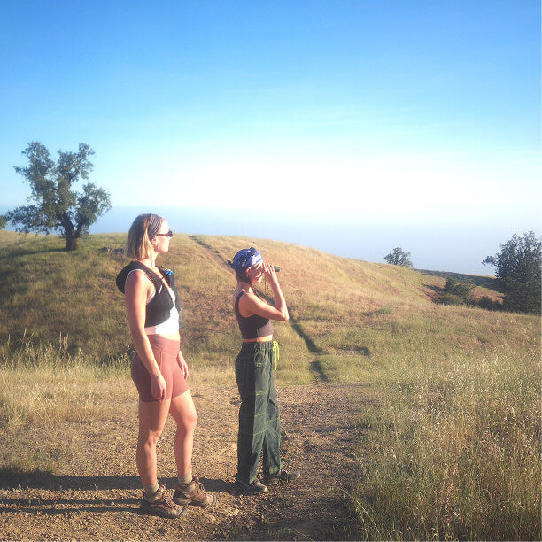 Two hikers looking out from a grassy ridge