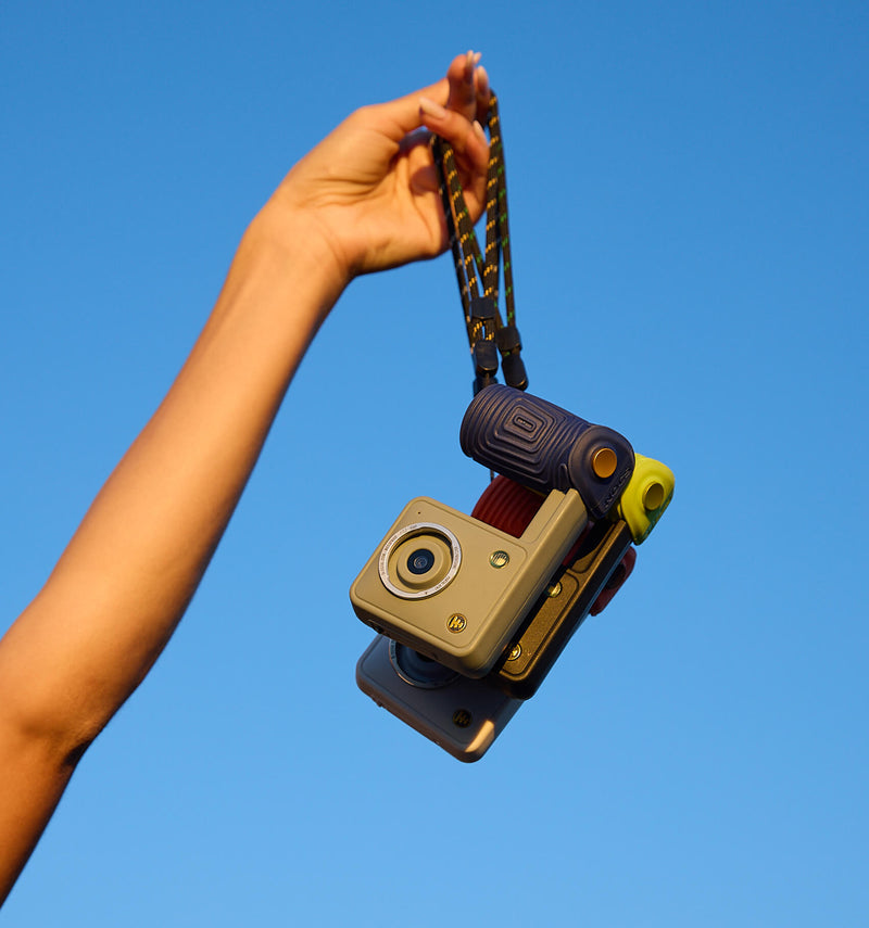 Hand holding three Portal AFN7 cameras by their straps against a blue sky