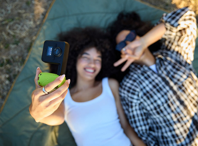 Two friends lying on a blanket taking a selfie with a black Portal AFN7
